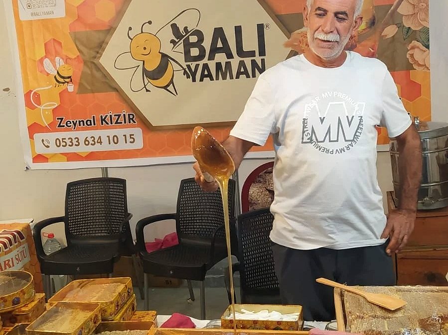 Zeynal Kizir, fuar standında tahta kaşıkla bal gösterirken